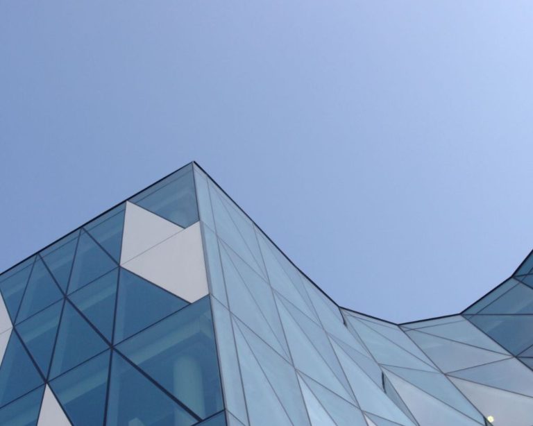 Angular blue glass building against a blue sky.
