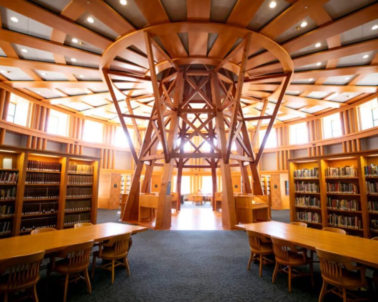 Denver Central Library interior with intricate wooden beams, bright light, grand bookcases, and long tables.