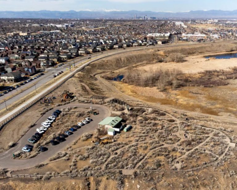 A cleared construction space for Bluff Lake Nature Center in Denver, Colorado. Image shows lots of cleared dirt with a lake in the distance.