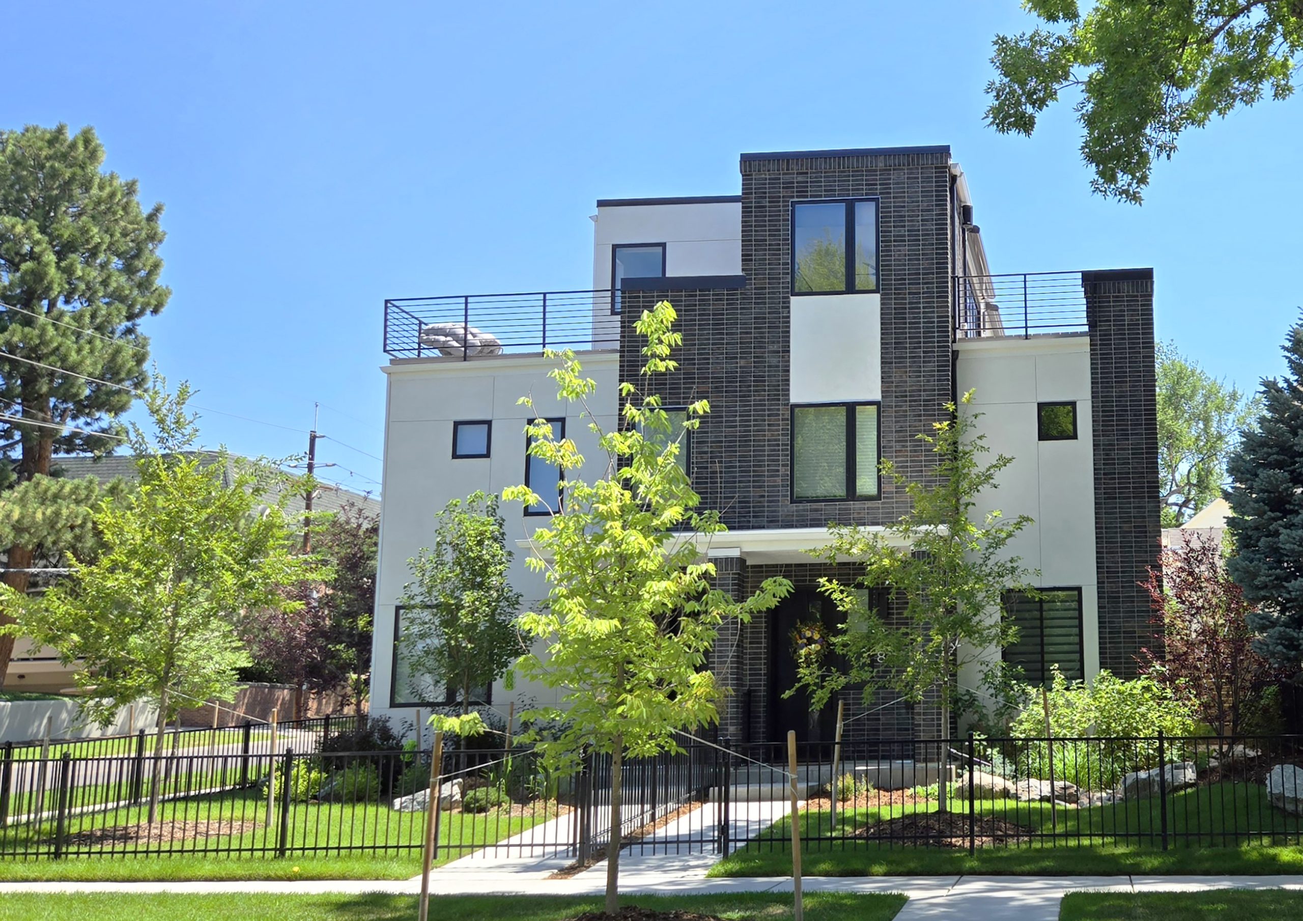 290-monroe-st Image of a contemporary luxury home with boxy shape, rooftop patio, and small trees in the front yard.