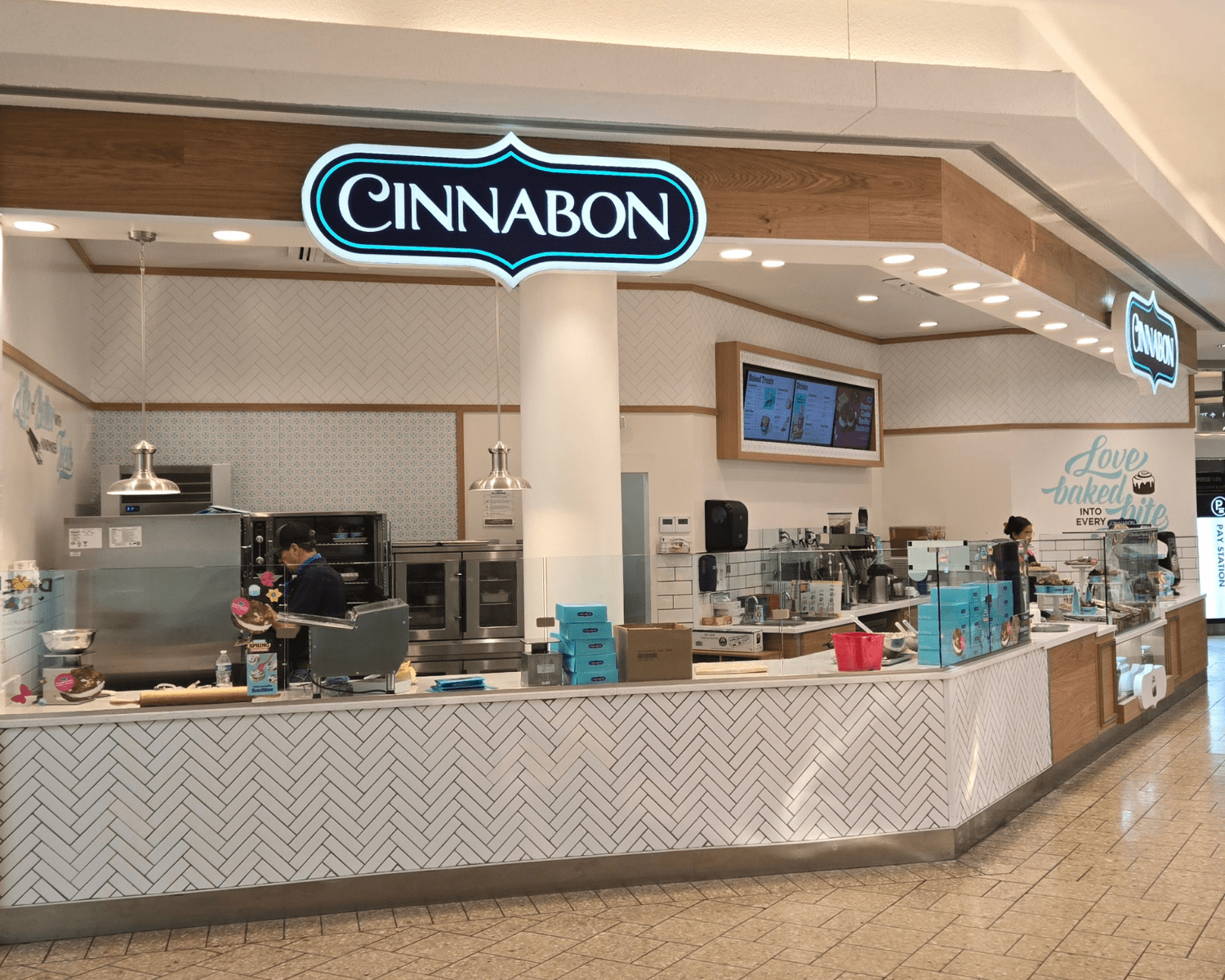 CINNABON-CHERRY-CREEK Image of a Cinnabon bakery inside of mall with lit sign, counter, and checkout area.