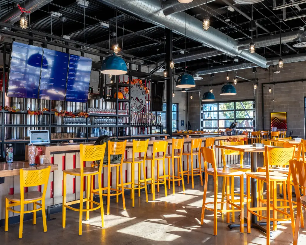 Image of a brewery interior with yellow stools and many beer taps.