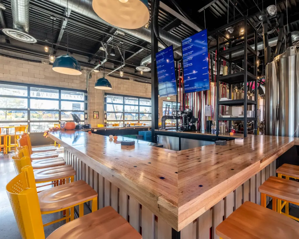Image of a brewery interior with wood bar, garage doors, and industrial look.