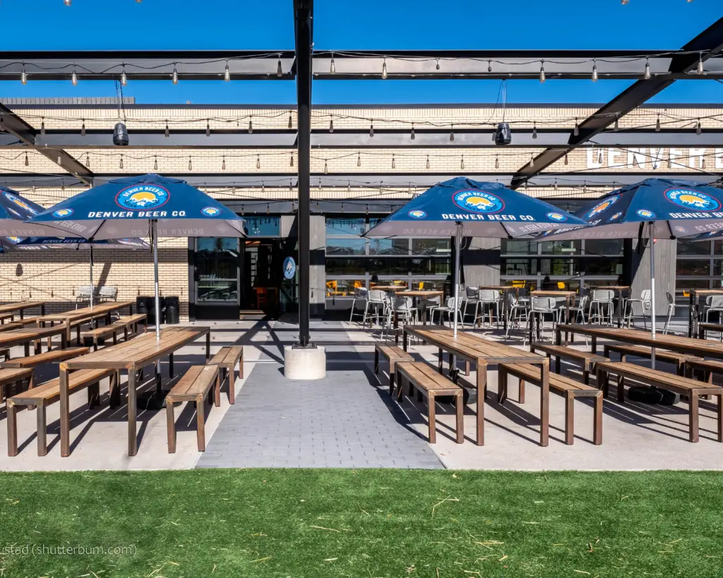 Image of a brewery patio with picnic tables and blue umbrellas.