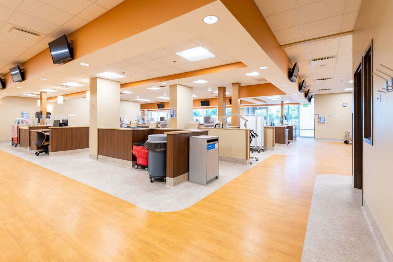FRESENIUS-KIDNEY-CARE-DENVER Image of a specialty medical facility with open area, ceiling lights, and wooden floors.