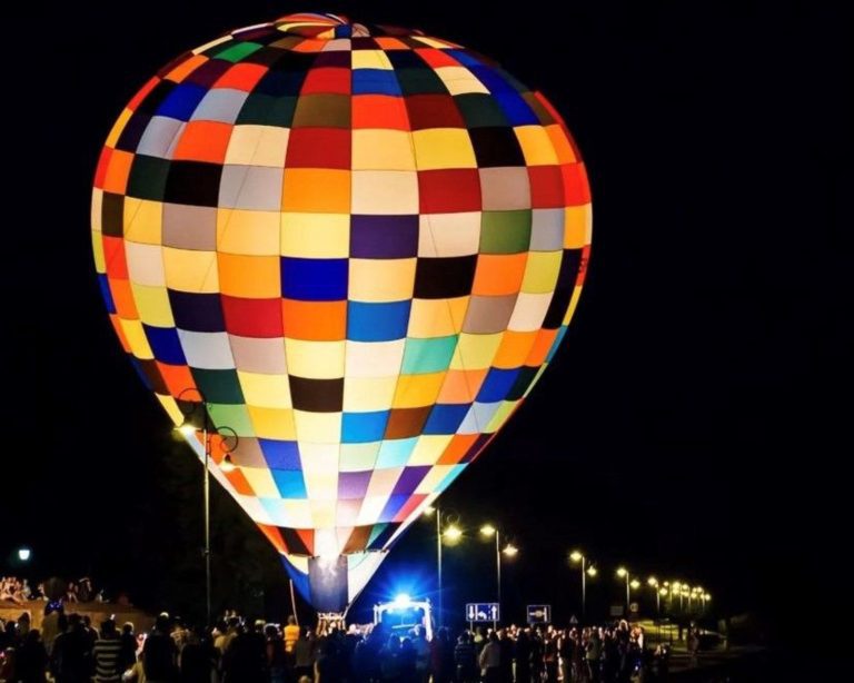 Image of colorful hot air balloon at night with crowd below.