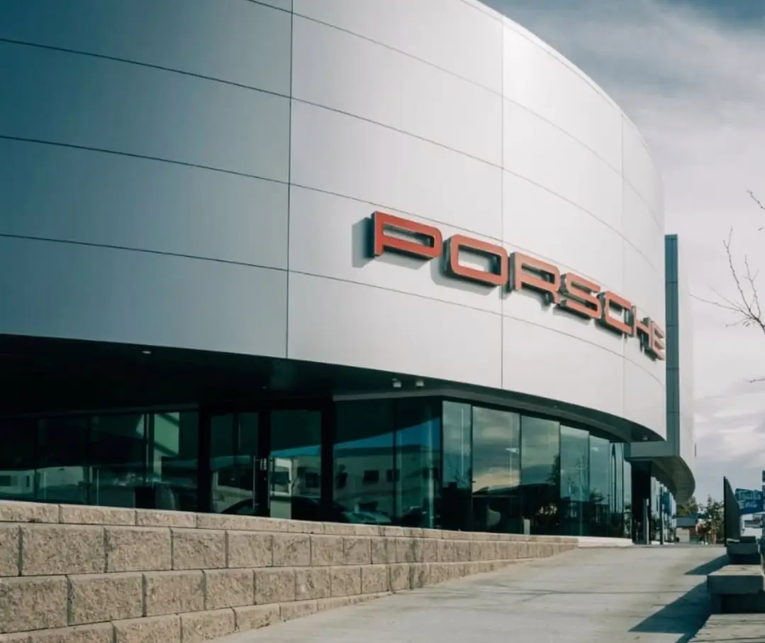 Image of a Porsche dealership facade with glass windows.