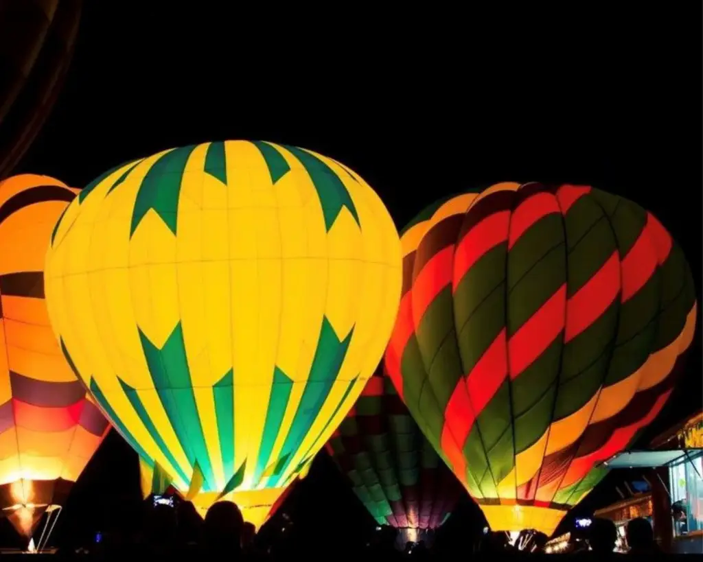 Hot air balloons lit up at night.