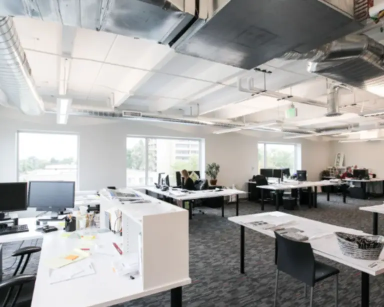 Image of an office building interior with work tables and desks.