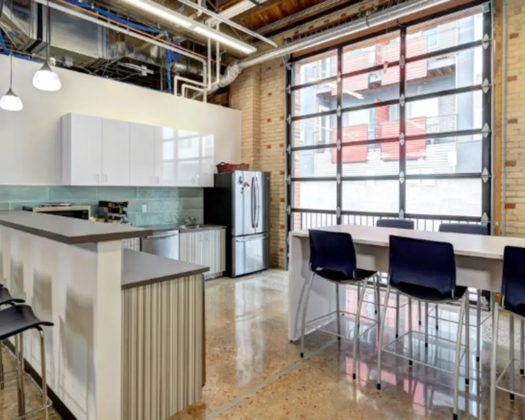 Image of an office building kitchen with chairs and appliances.