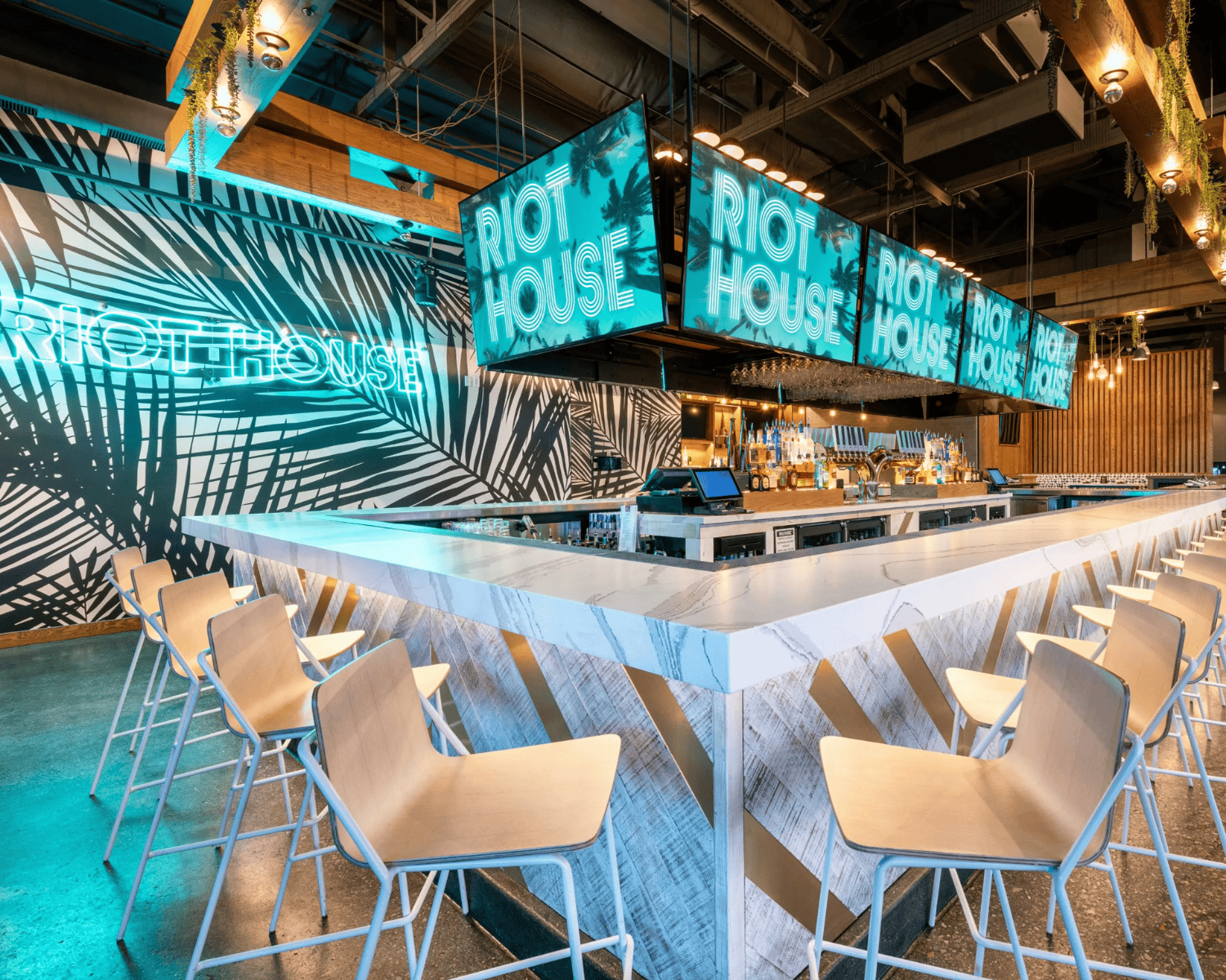 RIOT-HOUSE-DENVER-3 Image of Riot House night club interior with turquoise neon lights, sleek bar, and tall chairs.