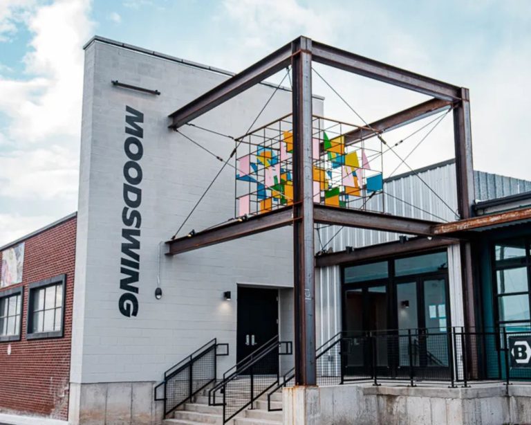 Moodswing Denver exterior with modern, boxy architecture, brand logo, and colorful modern art sculpture.