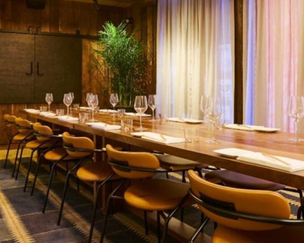 Uchiko Denver interior with long dining table and coordinating marigold yellow chairs.