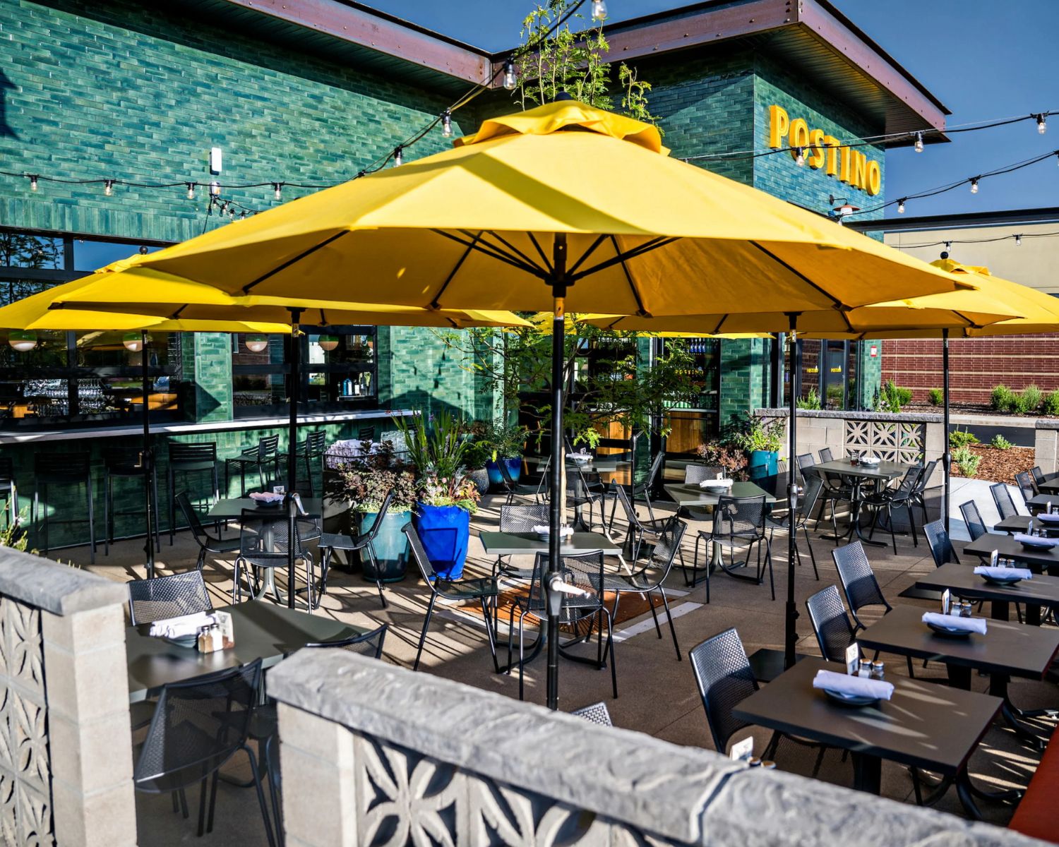 Outdoor patio with bright yellow umbrellas at Postino restaurant and wine bar in Westminster, Colorado.